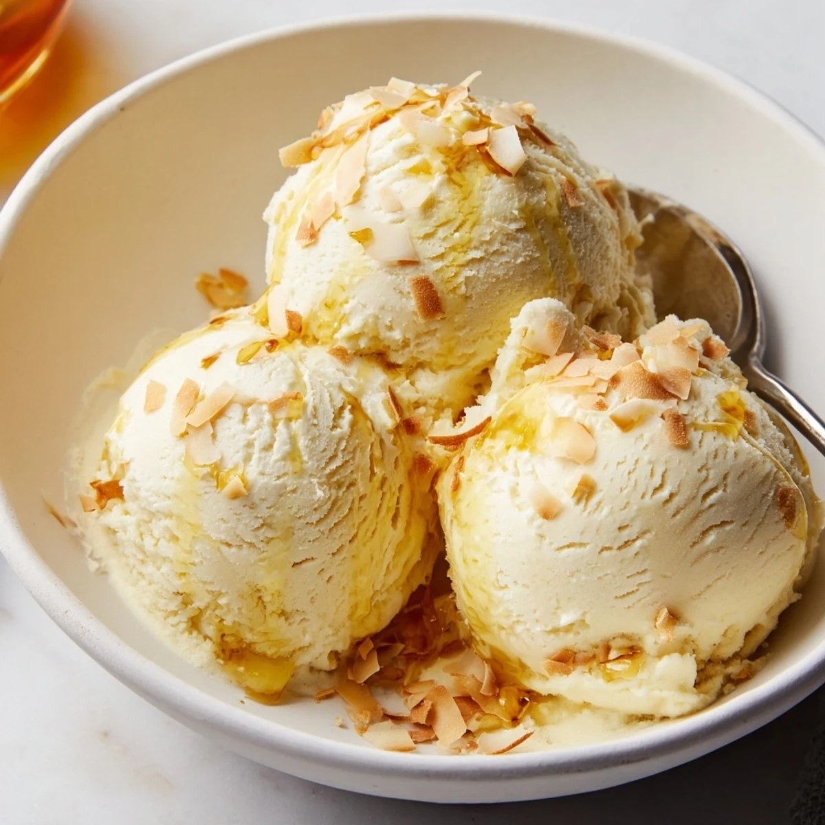A bowl of Creamy Pineapple Ice Cream topped with toasted coconut