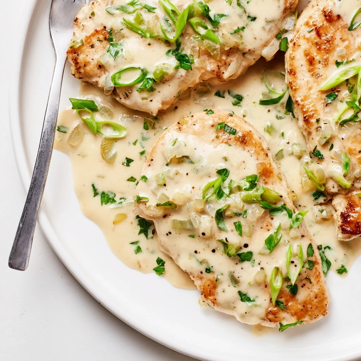Tender juicy chicken pieces coated in velvety garlic cream sauce dotted with colorful fresh herbs