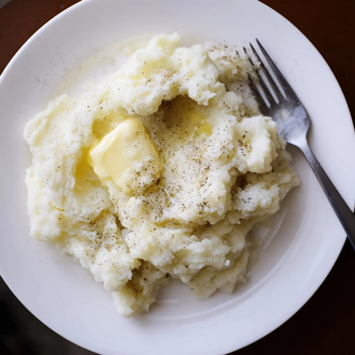 Fluffy homemade mashed potatoes with golden butter drizzled over the smooth white texture