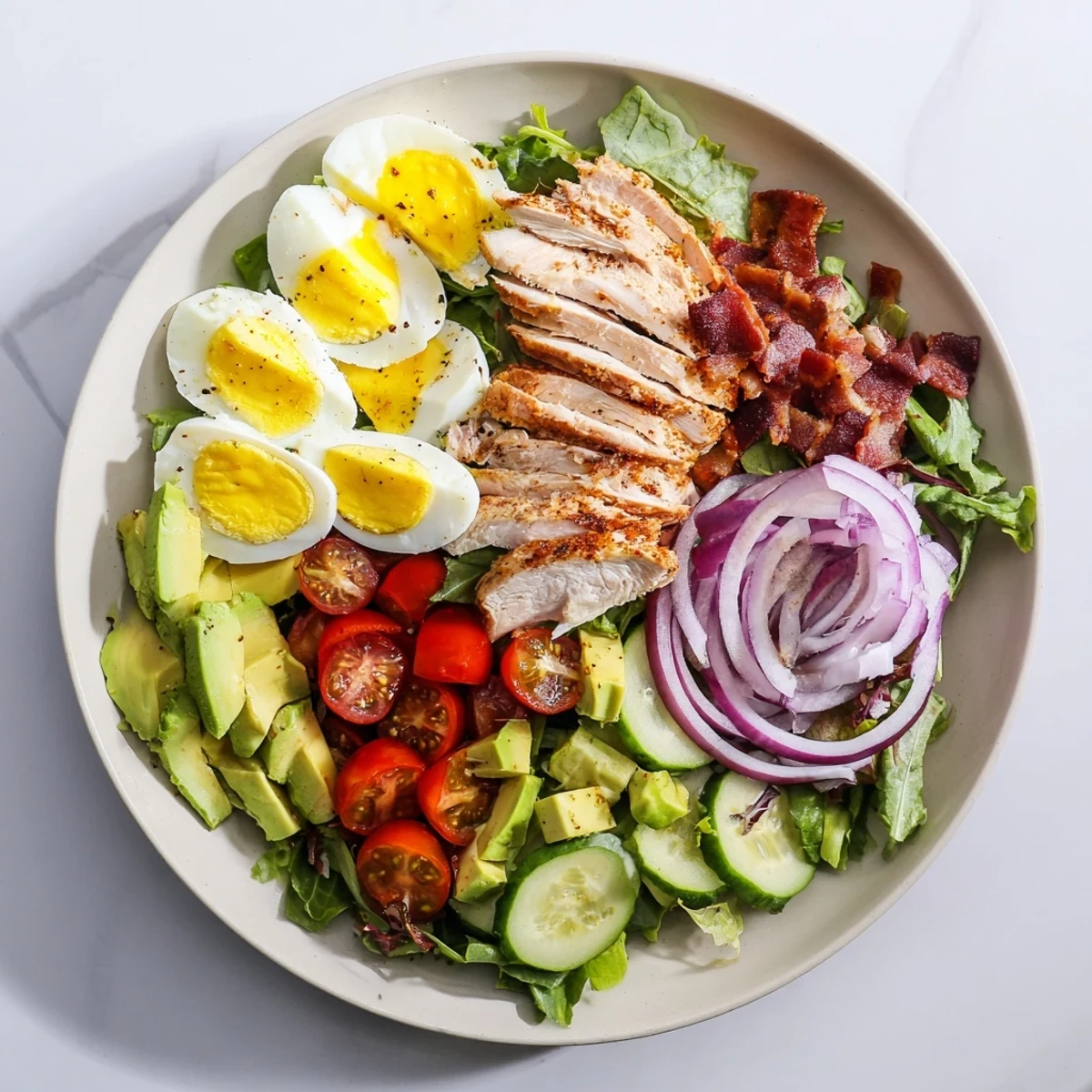 Paleo Grilled Chicken Cobb Salad topped with avocado, bacon, hard-boiled eggs, and fresh vegetables