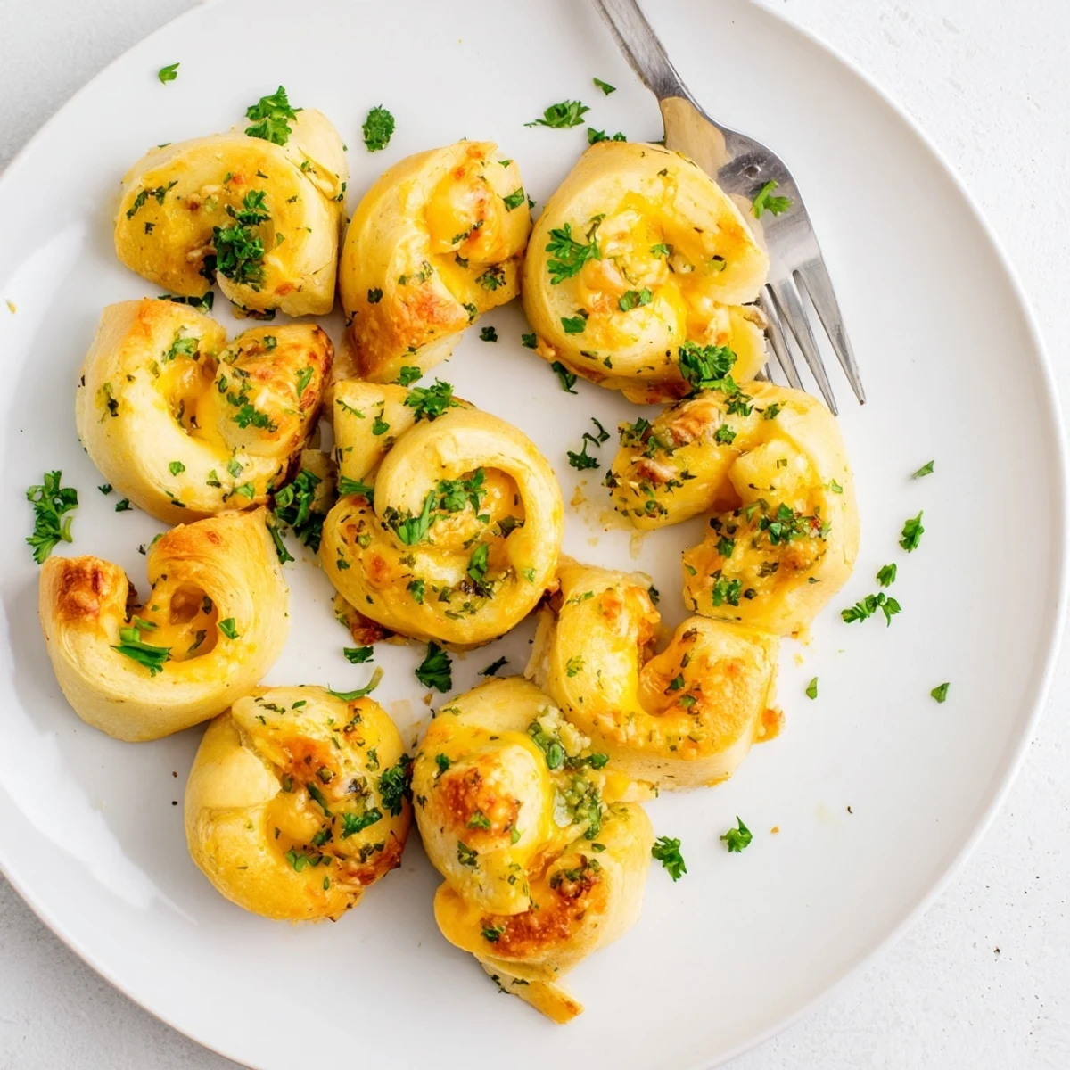Warm appetizer of cheesy garlic butter rollups brushed with parsley and served on platter