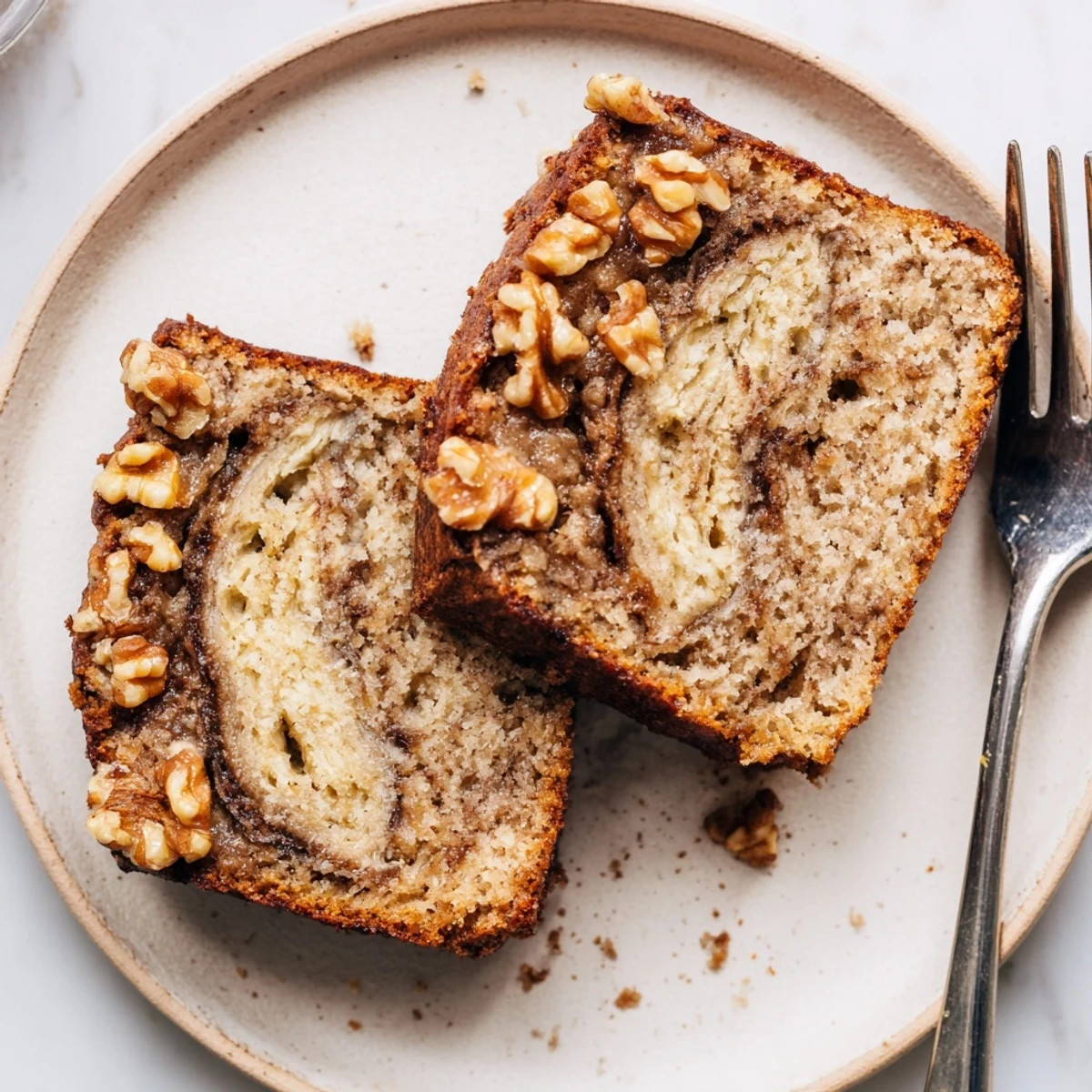Golden brown banana nut bread loaf with walnuts and a cinnamon sugar swirl on a wooden cutting board