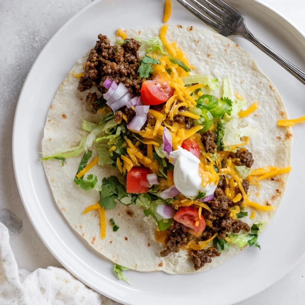 Golden brown smashed beef tacos with melted cheddar and Monterey Jack cheese on a sizzling Blackstone griddle