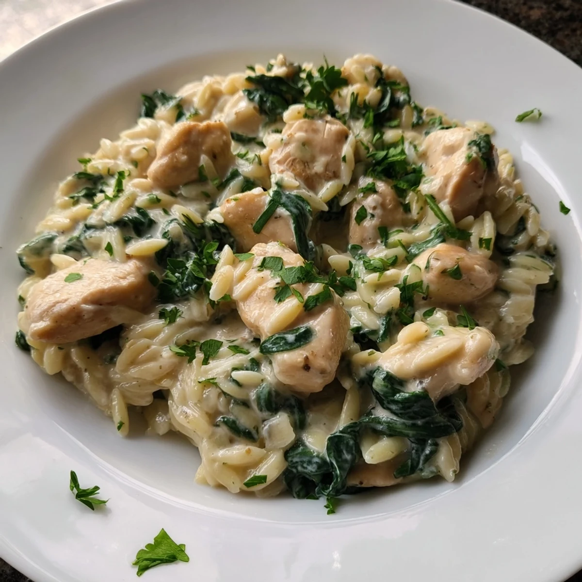 Rich single skillet chicken and orzo dish with melted herb cheese and fresh greens