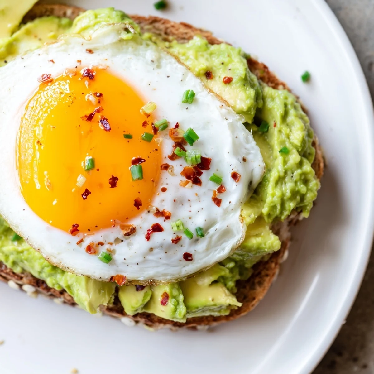 Whole grain bread piled high with ripe avocado and a sunny side up egg