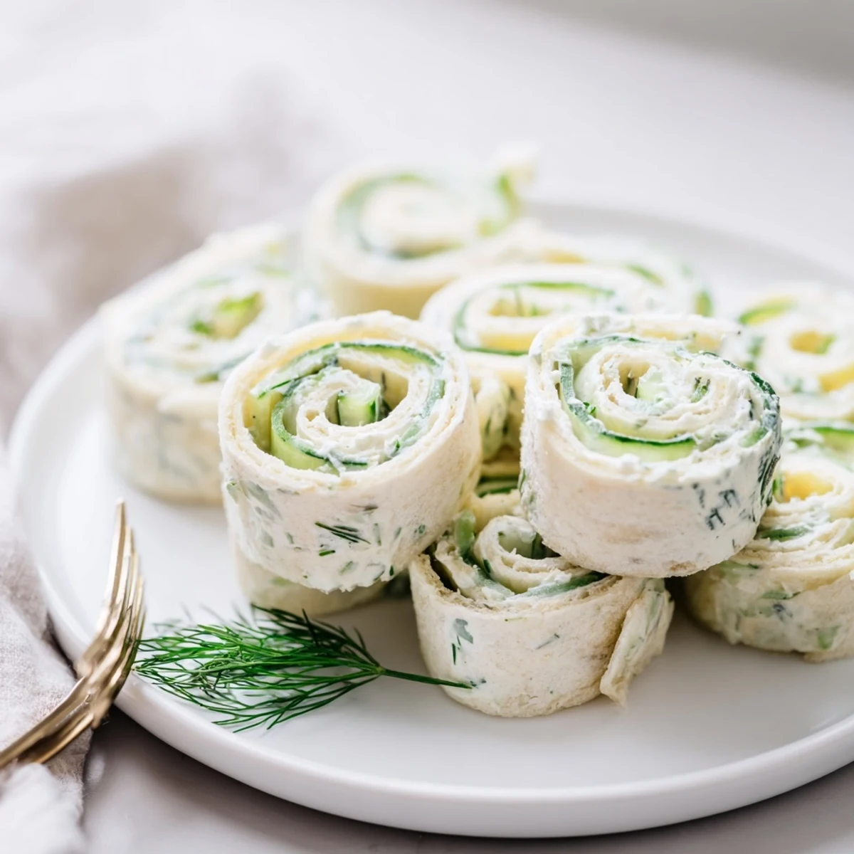 Cucumber And Dill Pinwheels chilled on a platter, creamy filling, fresh dill.