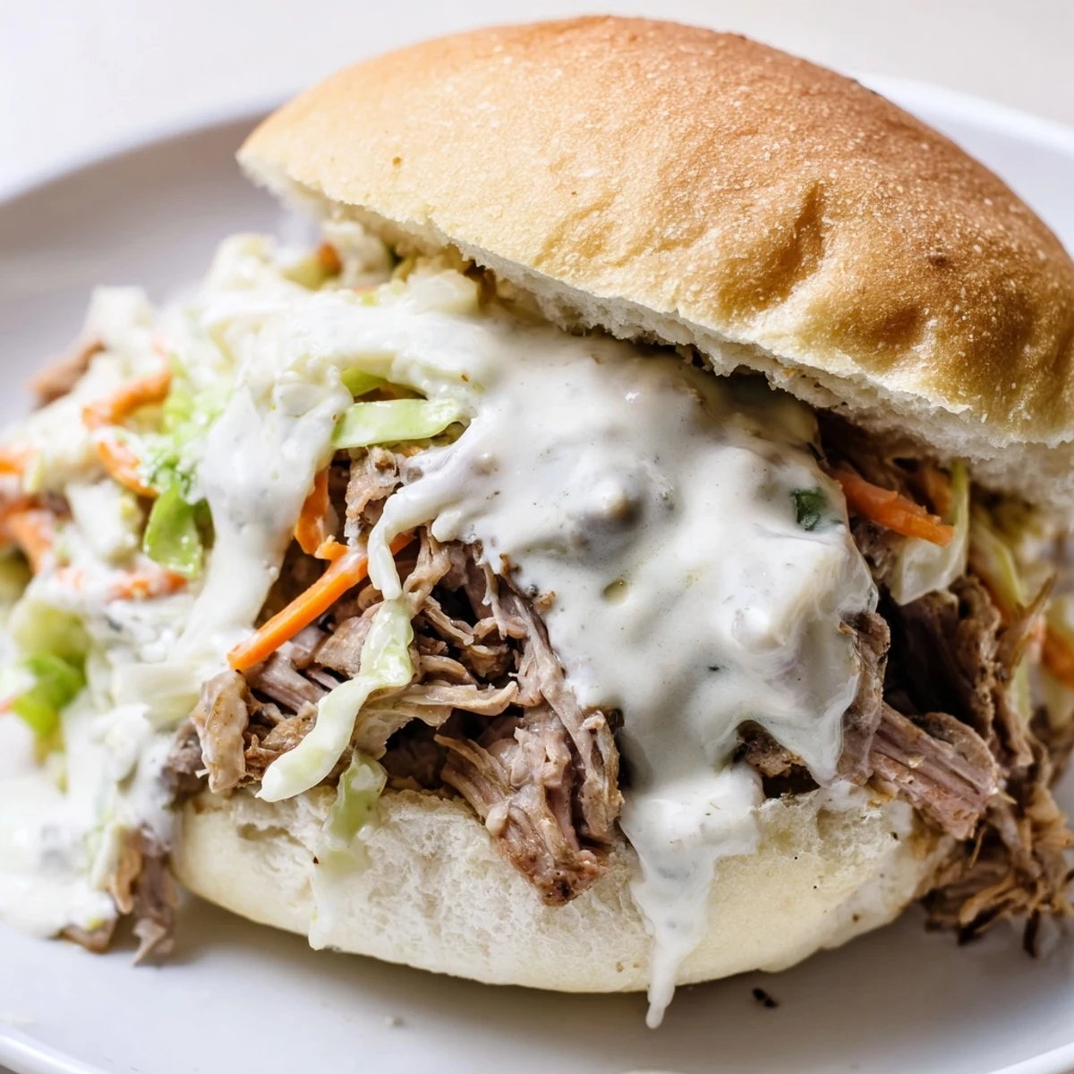 Tender shredded lamb shoulder glistening with tangy Alabama white sauce on soft golden slider rolls