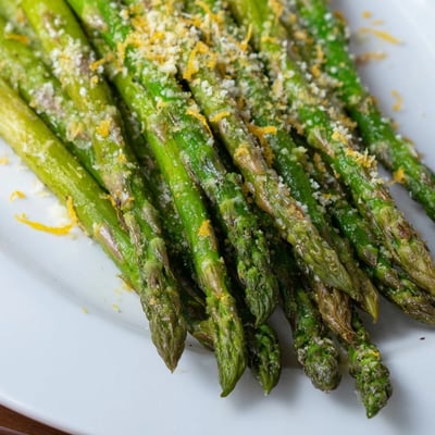 Golden roasted asparagus with Parmesan and lemon zest, ready to serve on a baking sheet.