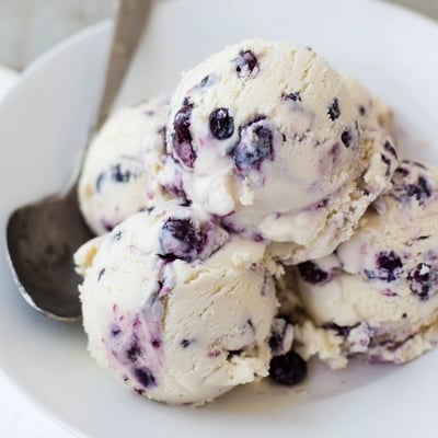 Blueberry Cottage Cheese Ice Cream is scooped into a serving dish, garnished with a mint leaf for a fresh summer dessert.