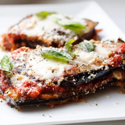 Smoky charred aubergine slices layered in Charred Aubergine Parmigiana with rich tomato sauce and melted Parmesan cheese.
