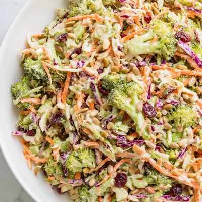 Vibrant Broccoli Slaw topped with dried cranberries, served at a sunny picnic