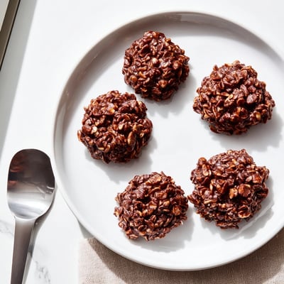 Chocolate oatmeal no bake cookies with crackled tops cooling on a rustic baking sheet